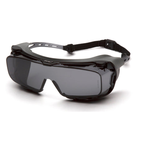 The Pyramex Cappture Safety Glasses S99_0STMRG, offered by Pyramex Safety, are designed with a sleek black wraparound style featuring a rubber gasket for added comfort and an adjustable strap. With tinted lenses that provide protection and clear visibility, their modern, aerodynamic frame ensures they are both functional and stylish.