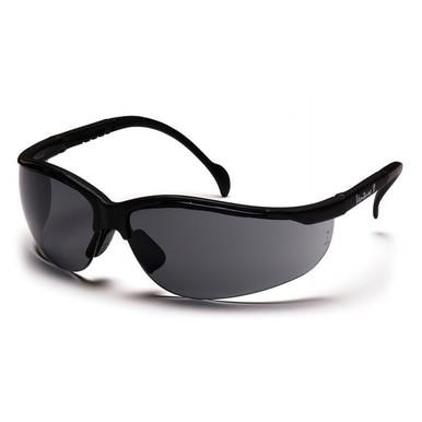 The Pyramex Venture II Safety Glasses from Pyramex Safety, featuring a sleek black wraparound frame with dark tinted lenses, rest on a white surface. Designed with a sporty curved style, these glasses provide UV protection to ensure your eye safety during any adventure.