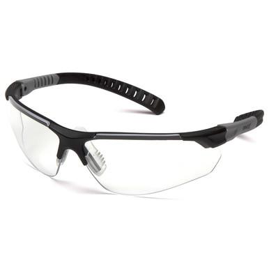 The Pyramex Sitecore Safety Glasses SBG101_0DTM, offered by Pyramex Safety, are a pair of clear safety glasses with black frames and gray temples that include an anti-fog coating. Their sleek, wraparound design makes them ideal for industrial applications. Angled gently, they rest against a white background.