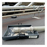 A metal hose connector sits in a black UltraTech Pellet Pond 8859 by UltraTech on asphalt, serving as part of a pellet containment system to capture scattered plastic granules during industrial piping work.