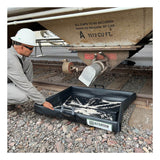 A worker in a hard hat places an UltraTech Pellet Pond 8859 under a railcar hopper to collect spilled granules on a gravel-covered railway track.