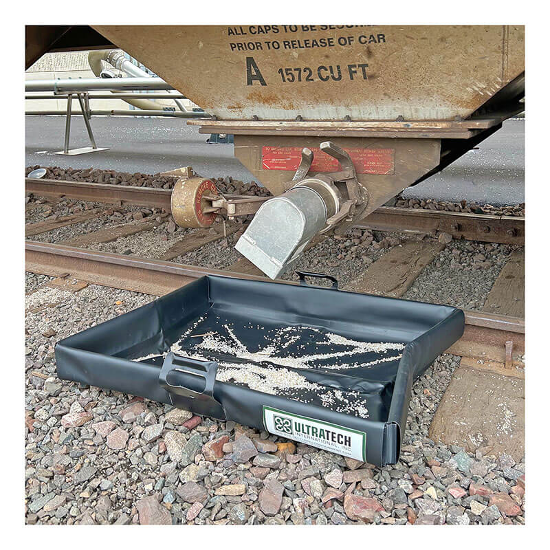 The UltraTech Pellet Pond 8859 is a black spill containment tray placed under a railcar valve to catch spilled plastic pellets or powder, preventing contaminants from reaching train tracks.