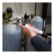 A person uses a BW Technologies by Honeywell Piston Hand Pump and colorimetric gas detection tubes to sample gas from a cylinder with gauges and valves in a laboratory.