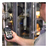 A person uses the RAE Systems PGM-2500 QRAE 3 Wireless Pumped Multi-Gas Monitor M020-11211-111 near pipes and industrial equipment to check gas levels in an industrial setting, with their face out of focus.