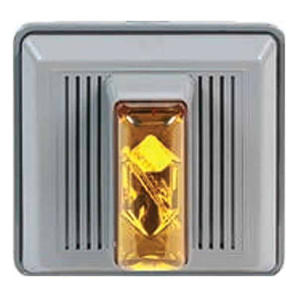 A gray rectangular wall-mounted emergency light, similar to an RKI 4 Wire Strobe/Horn by RKI Instruments, features a bright amber lens at the center. Designed with vertical ridges on either side of the lens, this fixture easily integrates into fixed systems for enhanced safety.