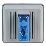 A gray square device, possibly an RKI Fixed System, incorporates a blue rectangular component in the center. Each side is adorned with vertical ridges similar to those on an Edwards 868STR, hinting at an RKI Instruments 4 Wire Strobe/Horn meant for outdoor panel mounting at 120 VAC, set against a plain white background.