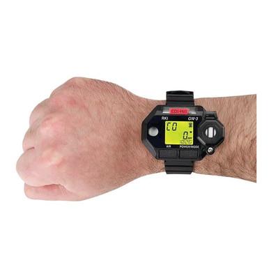 A person's hand is wearing a black digital watch with a rectangular face, similar to the RKI Instruments GasWatch 3 CO (-H2) Single Gas Monitor 73-0025. The watch display features a digital interface with numbers and symbols.