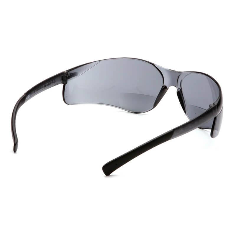 A pair of Pyramex Ztek Reader Safety Glasses S25_0R by Pyramex Safety, featuring wraparound black frames and dark, scratch-resistant, UV-protective lenses, shown from a rear side angle on a white background.