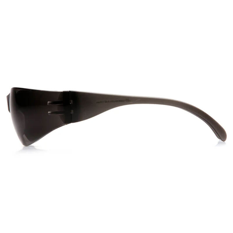 Side view of Pyramex Intruder Anti-fog Safety Glasses S41_0ST by Pyramex Safety, featuring a wide lens, impact protection, and curved arms, shown resting on a white surface.