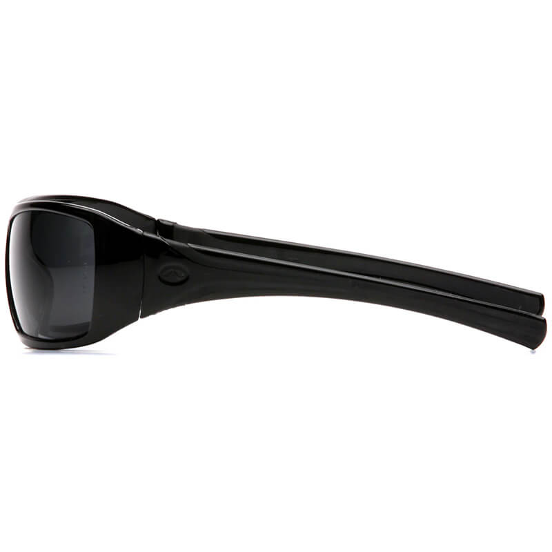 Side view of Pyramex Safety Goliath Safety Glasses (12/box) with black wraparound thick frames and dark lenses, providing stylish eye protection against a white background.
