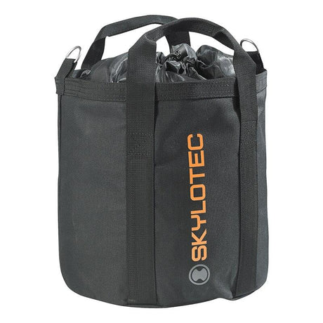 A Skylotec Rope Bag ACS-0009- in black, featuring orange branding on the side. The cylindrical design includes handles and a drawstring closure, making it ideal for storing climbing gear or safety equipment.