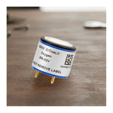 A close-up of a Replacement O2 Sensor for GasAlert Monitors SR-X2V by BW Technologies by Honeywell, showing its cylindrical shape, metal pins, and a warning label stating “DO NOT REMOVE LABEL,” resting on a wooden surface.