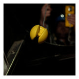 A close-up of the WatchGas Ball Float (Tubing NOT Included) SST-BALL-FLOAT by WatchGas, yellow and clam-shaped, is suspended by a wire with a blurred figure holding a yellow object in the dark background for confined space clearance.