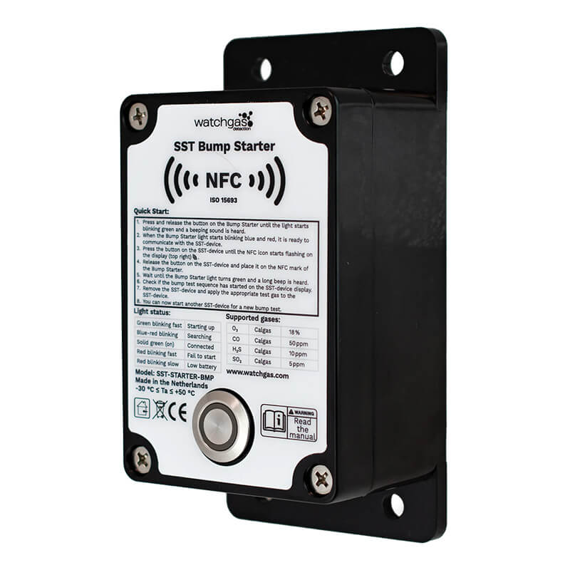 Black and white rectangular electronic device labeled “WatchGas SST1 Bump Test Starter SST1-BS” featuring the WatchGas brand, NFC symbol, mounting plate, buttons, indicator lights, quick start instructions, and technical details on its front panel—ideal as a portable safety tester or bump test starter for gas detector compliance.