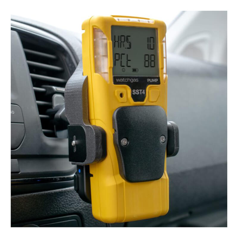 A yellow handheld gas detector with a digital display is mounted in a vehicle near an air vent, beside a WatchGas SST Range Wireless Car Charger SST-CAR-CHG from WatchGas.