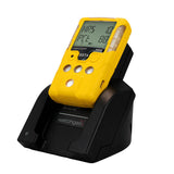A yellow handheld gas detector with a digital display rests on the WatchGas Induction Cradle Charger - Single Desktop w/Adapter, designed for industrial use and compatible with SST4 and SST5 detectors. The charger features the WatchGas brand logo.