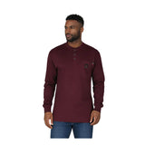 A man wears the ForgeFR Forge FR Henley MFRHNLY-004, a long-sleeve burgundy FR shirt with a chest pocket, and blue jeans against a plain white background.