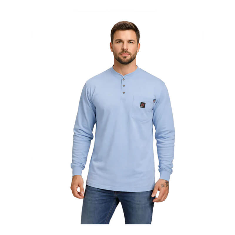 A man wearing a ForgeFR Forge FR Henley MFRHNLY-004 in light blue with long sleeves and a chest pocket, paired with blue jeans, stands facing forward against a plain white background.