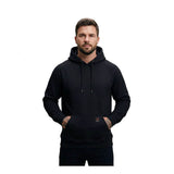 A man with short hair and a beard stands facing forward, wearing a ForgeFR Forge FR Pullover Hoodie MFRHDY0033 (ATPV 21 cal/cm²), his hands in the front pocket. The background is white.