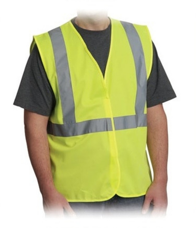 A person models the PK Safety Supply Test Product—a bright yellow safety vest with gray reflective stripes—over a dark short-sleeve shirt, standing against a plain white background.