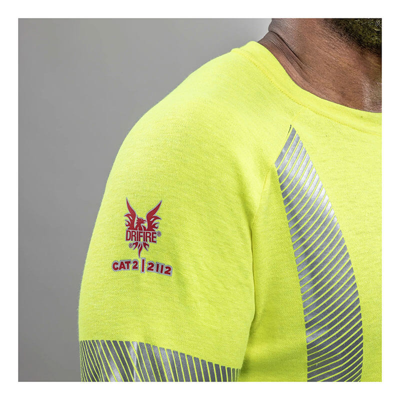 A close-up of the NSA DRIFIRE Helix FR Long Sleeve Hi-Vis T-Shirt Class 3 TEE-HXC3—a bright yellow shirt with silver reflective stripes, red "DRIFIRE" logo on the shoulder, and "CAT 2 | 2112" and Arc Rating 12 cal/cm² printed below.
