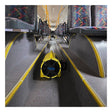 A Euramco RamFan UB20 18VDC blower, colored yellow, sits on the floor between rows of empty patterned seats inside a bus, facing toward the front.