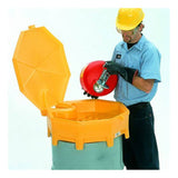 A worker wearing a hard hat, safety goggles, and gloves carefully pours liquid from a red container into a large yellow bin with an open lid using an UltraTech Global Funnel 049 by UltraTech International. The scene conveys industrial safety practices.