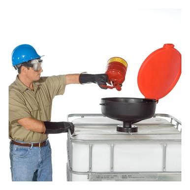 Dressed in a beige shirt, jeans, and black gloves for maximum protection, a worker pours liquid from a red container into a large white storage tank. While wearing safety gear that includes a blue helmet and goggles, they use an UltraTech International's UltraTech Burp-Free Model Drum Funnels 065_, designed for chemical resistance.