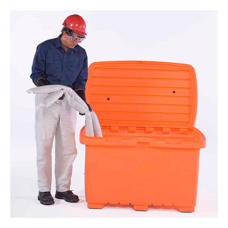 A person dressed in a blue shirt and light-colored pants, wearing a red hard hat, safety goggles, and work gloves, is placing a gray absorbent mat into an open UltraTech Utility Box 086_ from UltraTech International. This ensures all components of the spill kit are securely stored.