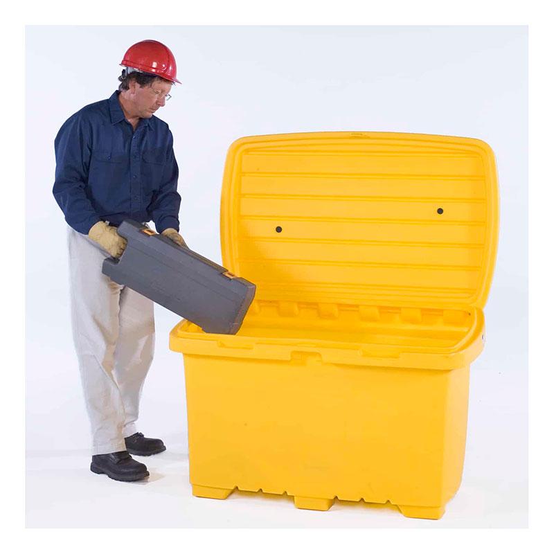 A person wearing a red helmet and gloves places an UltraTech Utility Box 086_ into a large open yellow spill kit, set against a plain white background.