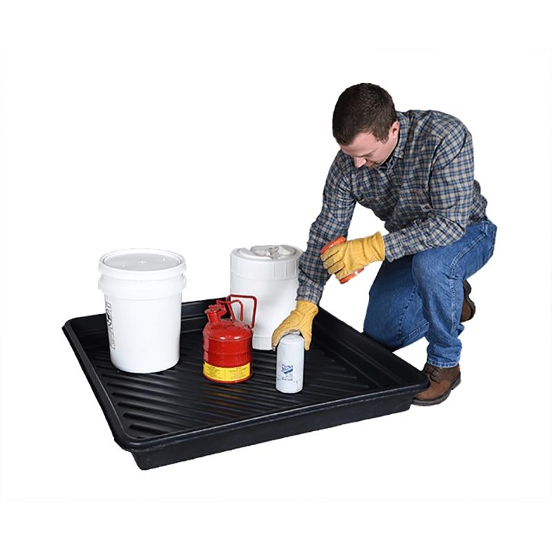 A man in a plaid shirt and gloves kneels beside an UltraTech Utility Tray 103_ by UltraTech International. The tray, made from heavy-duty polyethylene, supports two white buckets, a white container, and a red safety can. He is using a small white bottle, which could be a cleaning agent or lubricant.