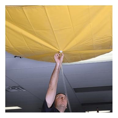 A person is reaching up to adjust a large yellow UltraTech Roof Drip Diverter 178_ attached to the ceiling. The image focuses on their arm extended upwards while they hold a string or cord, indicating an installation of the UltraTech International product for managing a leak emergency.