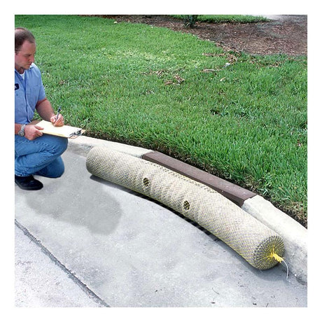 A person kneels on a sidewalk next to a storm drain protected by an UltraTech International UltraTech Gutter Guard. They are writing on a clipboard, surrounded by the green grass along the pavement, ensuring effective stormwater protection with recycled synthetic fibers.