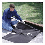 A person wearing gloves installs an UltraTech Reusable Model Drain Guard, a high-capacity black fabric cover by UltraTech International, over a storm drain on the side of a road, near grass. They are using a tool to secure this reusable drain guard during the installation process.