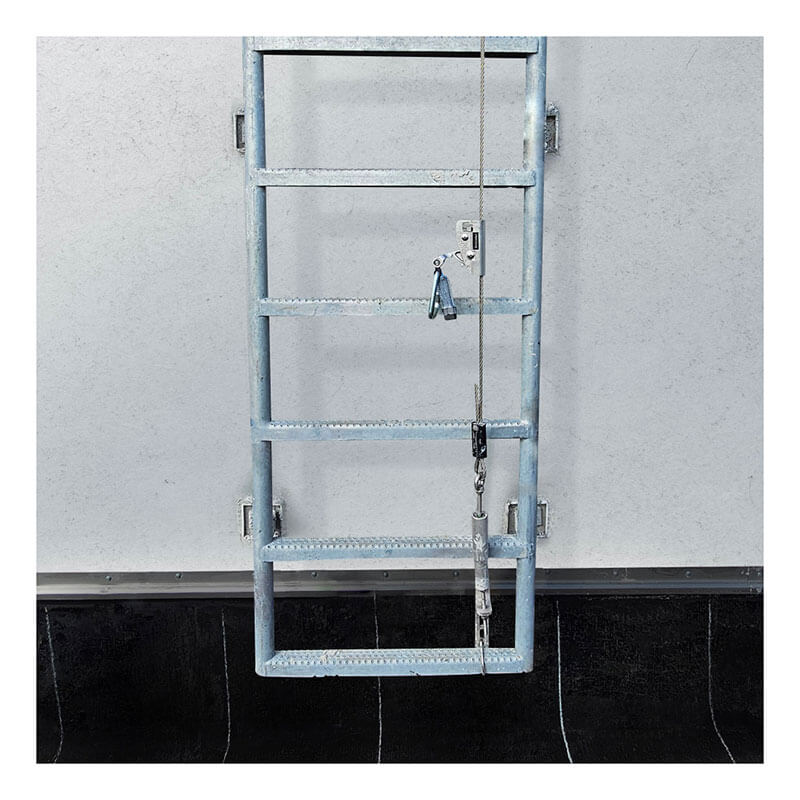 The Frontline Cable Vertical Lifeline System VLCS by Frontline Fall Protection runs down the center of this five-rung metal ladder, ensuring essential fixed ladder safety against a white wall above a black surface.