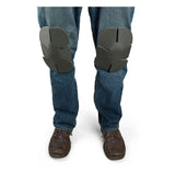 A person wearing blue jeans with Working Concepts Soft Knees Disposable Knee Pads 1012 and brown shoes. The gray knee pads, designed by Working Concepts, feature multiple sections for ultimate flexibility. The image highlights the lower legs, emphasizing the area from the knees downward.