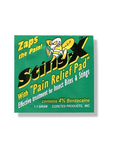 A green package labeled "Coretex Sting-X with Pain Relief Pads" features a cartoon bee and text promoting first aid for insect bites and stings. This pad contains 4% Benzocaine for effective pain relief, weighing 1.1 grams. It is manufactured by Coretex Products, Inc.