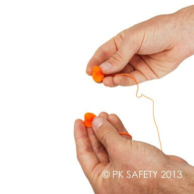 Close-up of two hands holding a pair of Howard Leight Quiet Reusable QD30 Corded Earplugs in orange, designed for noise reduction. The background is white. © PK Safety 2013.