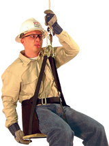 A construction worker, equipped with French Creek Production's fall protection gear, is suspended from a rope while sitting on the French Creek Deluxe Work Seat 4153. Wearing a hard hat, safety glasses, gloves, a beige shirt, and blue jeans, he confidently displays this Made in the USA equipment.