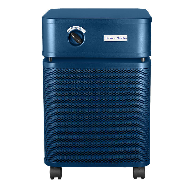 The Austin Air Systems Bedroom Machine B402 is a blue rectangular air purifier with a medical grade HEPA filter, a top-front control knob, "Bedroom Machine" label, and four small wheels.