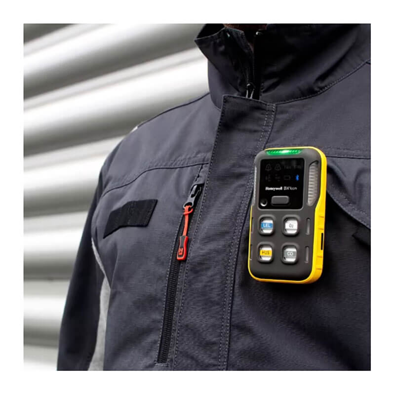 A person wears a dark gray jacket with a BW Technologies by Honeywell BW Icon 4-Gas Detector (LEL, O2, H2S, CO) ICON-Y-H clipped to the chest, which features several buttons and a small display screen.
