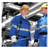 Two workers in blue protective uniforms, gloves, and helmets stand in an industrial facility with metal pipes in the background. Both wear safety goggles and communication devices clipped to their uniforms, each equipped with a GfG G999S 4 Gas Detector with Integrated Pump from GfG to monitor for multi-gas hazards during confined space entry.