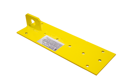 The French Creek Reusable Double Plate Roof Anchor MRA-R from French Creek Production is a yellow metal bracket featuring multiple holes and a welded tab with a circular hole, specifically designed for fall protection. It comes with a white label at the center and is perfect for use as a reusable roof anchor. The background is plain.