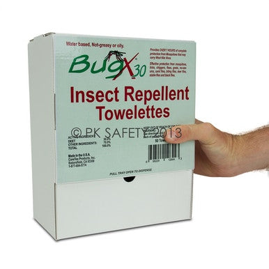 A hand holds a box of Coretex BugX30 Wall Mount Towelettes 50/Box 12644. The white packaging, featuring green and red text, emphasizes its DEET-infused formula as water-based, non-greasy, and non-oily, with a convenient dispensing slot located at the bottom.