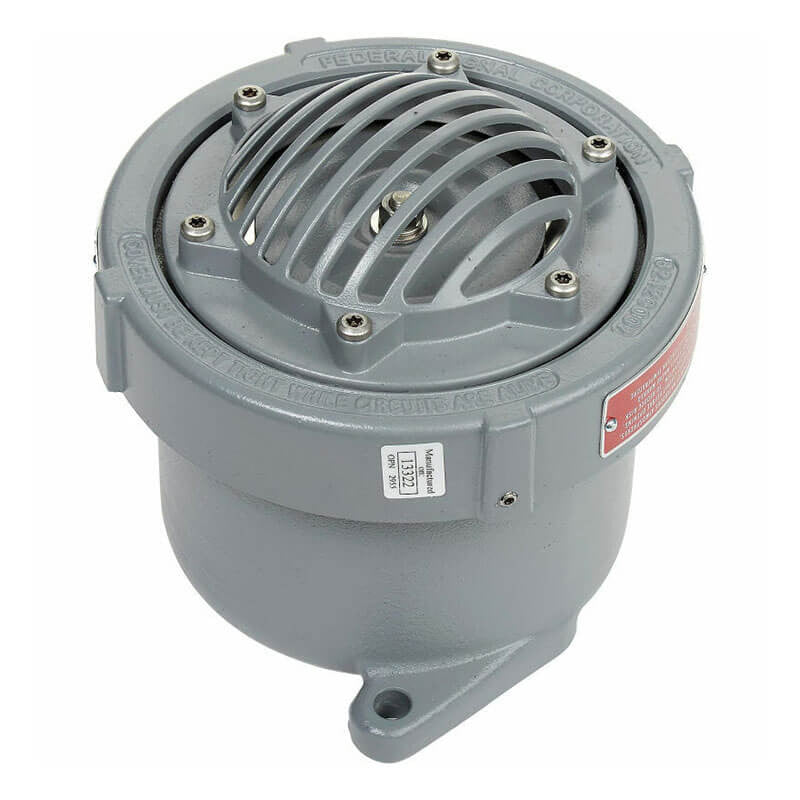 A gray, cylindrical RKI Vibrating Horn from RKI Instruments features a protective grill on top and a label on its side. Designed for hazardous locations, the Federal Signal device has an inscribed metal surface around its perimeter. The explosion-proof base includes mounting holes for easy installation and operates on 120 VAC (Class I, Div 1).