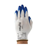 A hand wearing a white Ansell HyFlex Nitrile Dipped Glove 11-900 with blue fingertips and printed text, featuring a durable nitrile coating for enhanced abrasion resistance, is shown palm down against a white background.