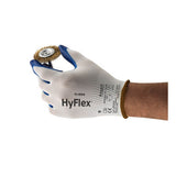 A hand wearing an Ansell HyFlex Nitrile Dipped Glove 11-900, renowned for its excellent abrasion resistance, holds a small wire brush wheel with a metal center against a white background.
