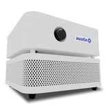 The Austin Air Systems "it" Machine C100 is a compact white air purifier with a black front control knob, perforated lower section for particle removal, and four short legs for stability.