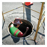 A worker in a hard hat and safety vest descends into a manhole, holding the RKI Instruments GX-3R 4 Gas Confined Space Monitor (72-RA-C). Safety barriers and an orange cone surround the area on the pavement.
