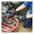 A person wearing MCR Safety Memphis Black Kevlar Cut Protection Gloves 9178NF adjusts the exposed mechanical parts of a red lawnmower with a tool. Only their arms and part of a blue shirt are visible.